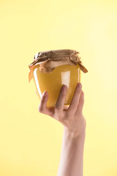 Обрізаний вид жінки, що тримає скляну банку зі смачним медом ізольовано на жовтому — стокове фото