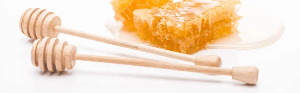 Panoramic shot of honeycomb with honey near wooden honey dippers on white background — Stock Photo