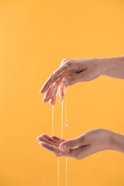 Recortado vista de la mujer mostrando las manos en goteo miel aislado en naranja - foto de stock