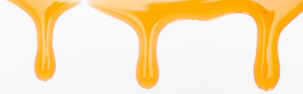Tiro panorâmico de gotejamento doce mel saboroso isolado no branco — Fotografia de Stock