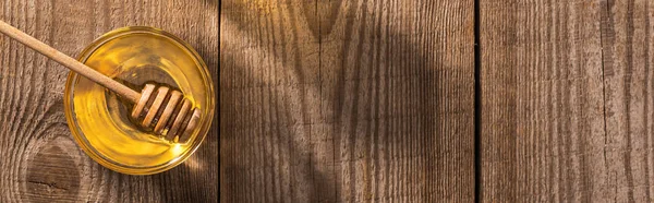 Colpo panoramico di ciotola di vetro con miele e tuffatore di miele sul tavolo di legno — Foto stock