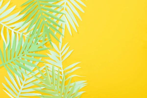 Vista superior do papel cortar folhas tropicais verdes no fundo brilhante amarelo com espaço de cópia — Fotografia de Stock