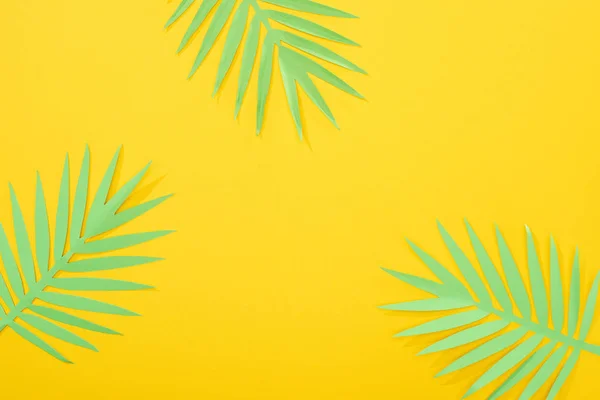 Top view of paper cut green tropical leaves on yellow bright background with copy space — Stock Photo