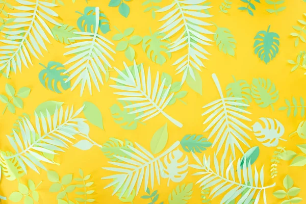 Vue du dessus des feuilles tropicales vertes coupées en papier sur fond jaune brillant avec espace de copie — Photo de stock