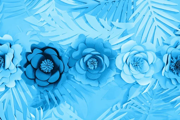 Tendido plano con hojas de papel cortado y flores sobre fondo azul - foto de stock