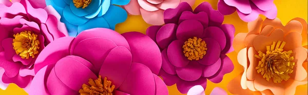 Plat couché avec du papier coupé multicolore fleurs brillantes sur fond jaune — Photo de stock