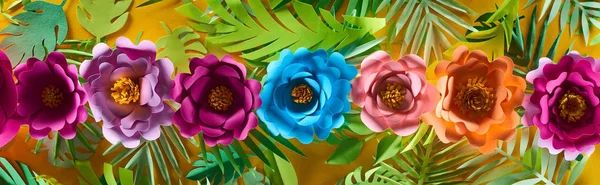 Flache Lage mit Papierschnittblumen auf tropischen Blättern auf gelbem, hellem Hintergrund, Panoramaaufnahme — Stockfoto