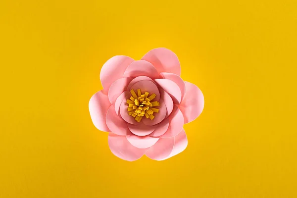 Top view of paper cut pink flower on yellow background — Stock Photo