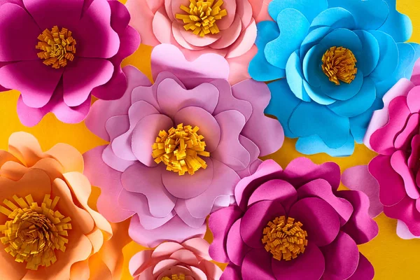 Vue du dessus de papier coupé multicolore fleurs vives sur fond jaune — Photo de stock