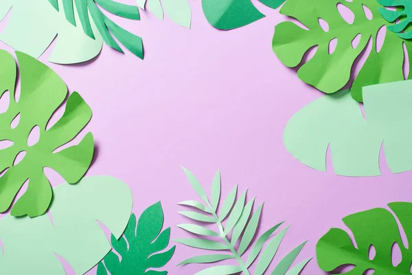 Vista superior do papel verde cortar folhas tropicais no fundo violeta com espaço de cópia — Fotografia de Stock