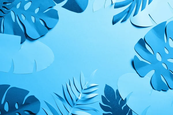 Paper cut exotic leaves on blue minimalistic background with copy space — Stock Photo