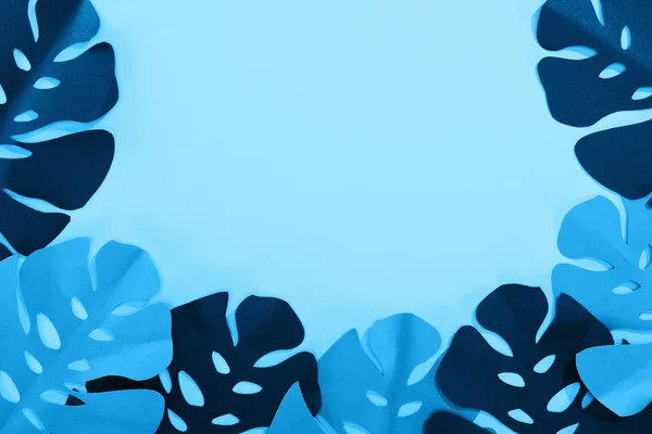 Вид зверху на папір вирізане тропічне листя на синьому мінімалістичному фоні з пробілом для копіювання — стокове фото