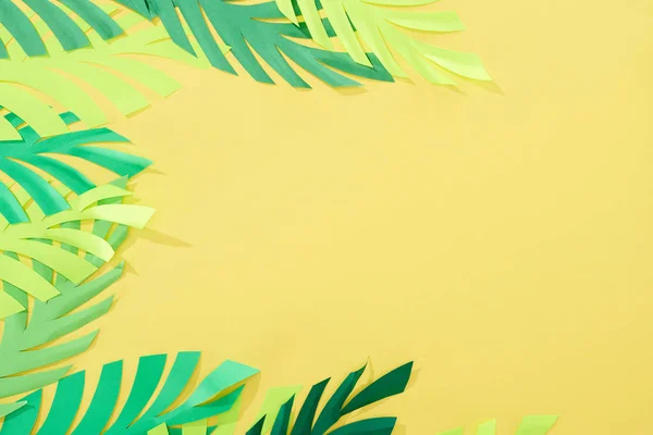 Vue du dessus des feuilles tropicales vertes coupées en papier sur fond jaune brillant avec espace de copie — Photo de stock