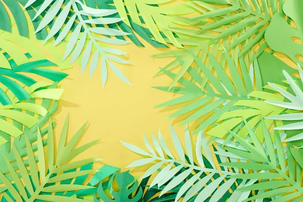 Top view of paper cut green tropical leaves on yellow bright background with copy space — Stock Photo