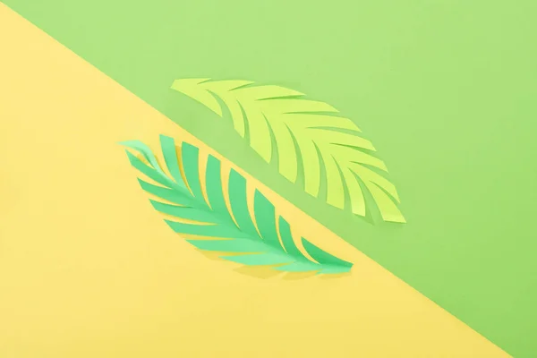 Flat lay with paper cut tropical leaves on yellow and green bright background — Stock Photo