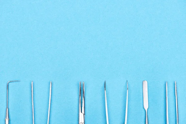 Vista superior del conjunto con instrumentos dentales metálicos aislados en azul - foto de stock