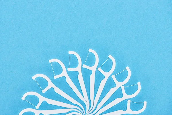 Vista superior de palillos de dientes de hilo blanco y plástico aislados en azul - foto de stock