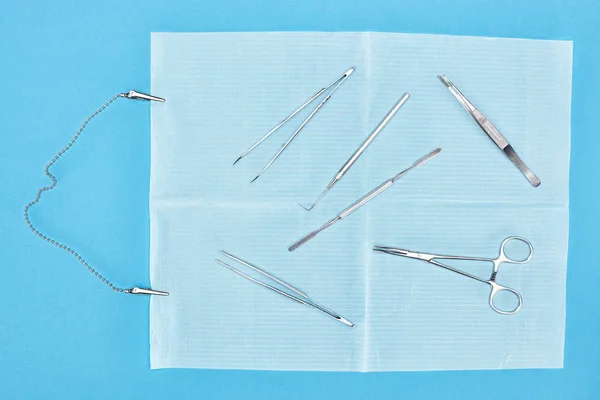 Vista superior do conjunto com instrumentos odontológicos sobre avental com clipes metálicos isolados em azul — Fotografia de Stock