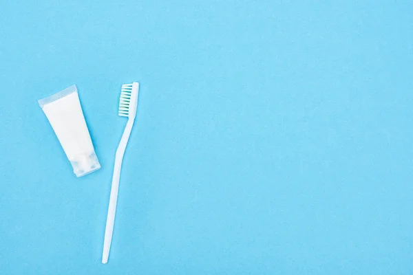 Вид зверху на білу зубну щітку і зубну пасту ізольовано на синьому — стокове фото
