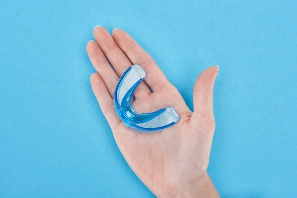 Vista recortada de la mujer sosteniendo retenedor en la mano aislado en azul - foto de stock