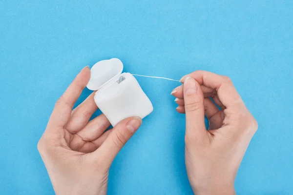 Cropped view of woman holding dental floss on blue — Stock Photo