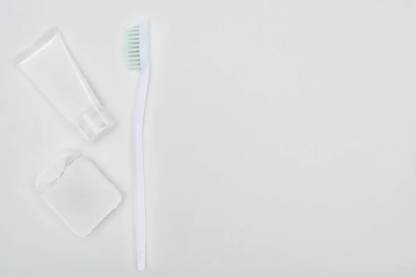 Vue du dessus de la brosse à dents et du dentifrice près des dents fil dentaire isolé sur blanc — Photo de stock