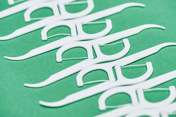 Selective focus of white and plastic floss toothpicks isolated on green — Stock Photo