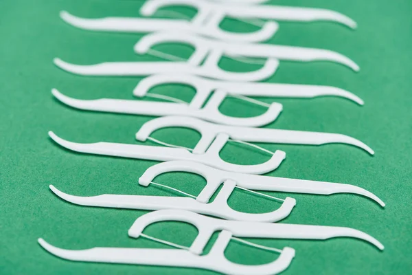 Selective focus of white floss toothpicks isolated on green — Stock Photo