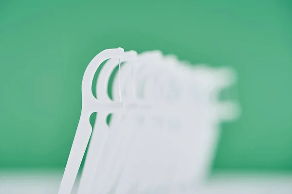 Selective focus of white floss sticks isolated on green — Stock Photo