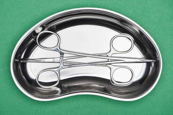 Top view of stainless scissors in metallic plate isolated on green — Stock Photo