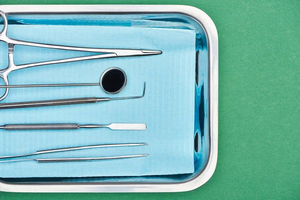 Top view of set with dental tools in metallic plate isolated on green — Stock Photo