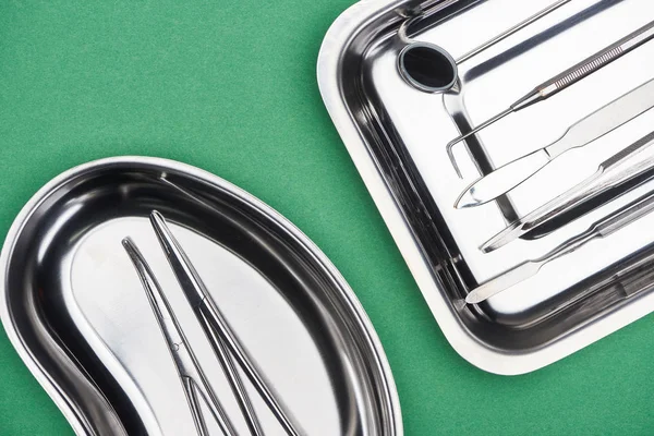 Top view of set with dental tools in metallic plates isolated on green — Stock Photo
