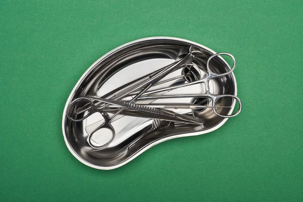 Top view of metallic plate with set of dental tools and scissors isolated on green — Stock Photo