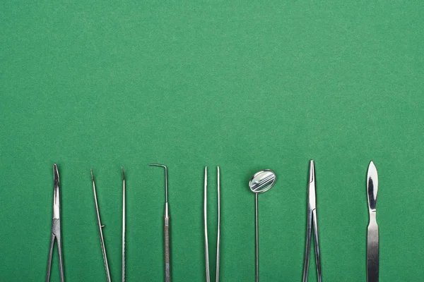 Вид зверху набір з нержавіючими зубними інструментами ізольовані на зеленому — стокове фото