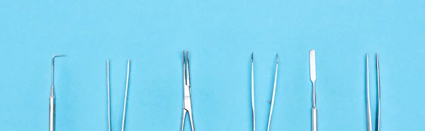 Панорамный снимок набора с металлическими зубными инструментами, изолированными на синем — стоковое фото