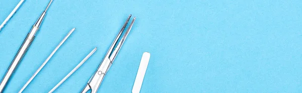 Panoramic shot of set with stainless dental instruments isolated on blue — Stock Photo