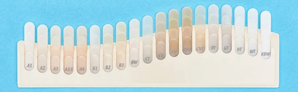 Panoramic shot of teeth samples with different shades isolated on blue — Stock Photo