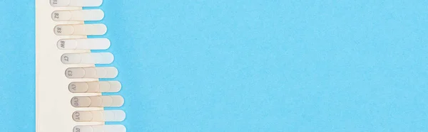 Панорамный снимок палитры зубов с различными оттенками, выделенными на голубом — стоковое фото