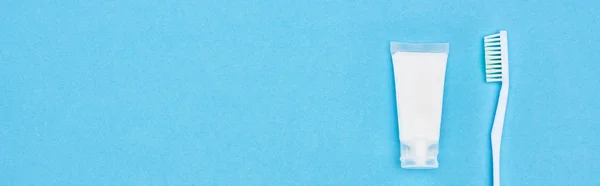 Panoramic shot of toothbrush and toothpaste isolated on blue — Stock Photo