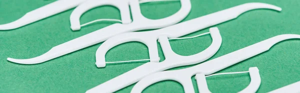 Plano panorámico de palillos de dientes de hilo blanco y plástico aislados en verde - foto de stock