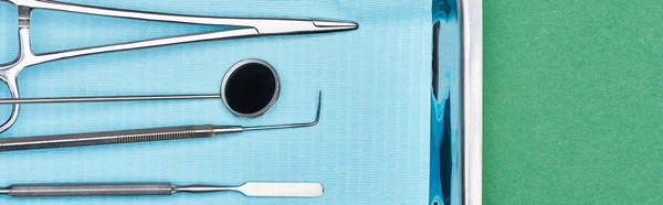 Panoramic shot of set with dental tools in metallic plate isolated on green — Stock Photo
