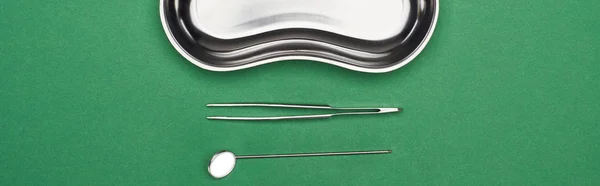 Панорамный снимок стоматологических инструментов возле металлической плиты, изолированной на зеленом — стоковое фото