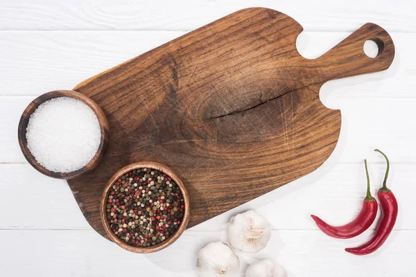 Top view of cutting board, chili peppers, salt, garlics and spices — Stock Photo