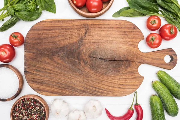 Top view of cutting board, cherry tomatoes, greenery, chili peppers, salt, cucumbers, garlics and spices — Stock Photo