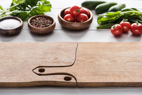 Enfoque selectivo de tablas de cortar, tomates cherry, vegetación, pepinos, sal y especias - foto de stock