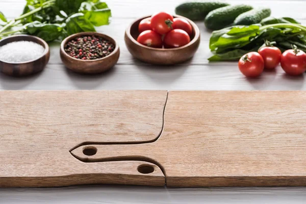 Selective focus of cutting boards, cherry tomatoes, greenery, cucumbers, salt and spices — Stock Photo
