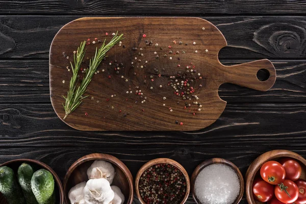 Top view of cutting board, cherry tomatoes, greenery, salt, garlics, cucumbers and spices — Stock Photo