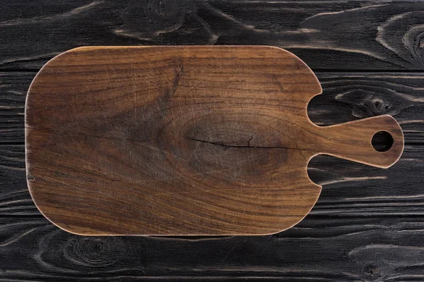 Top view of wooden cutting board on black table — Stock Photo