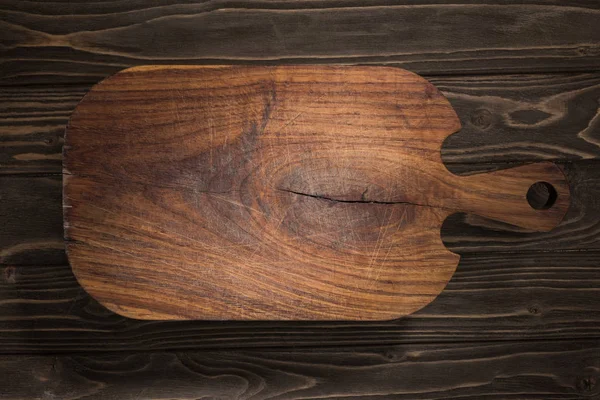 Top view of wooden cutting board on brown table — Stock Photo