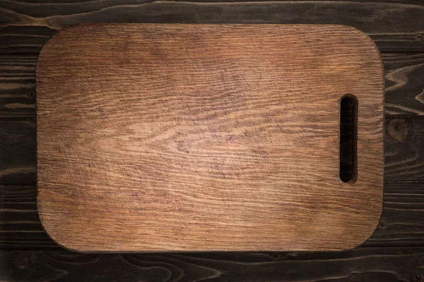 Vista superior de tabla de cortar de madera sobre mesa negra - foto de stock